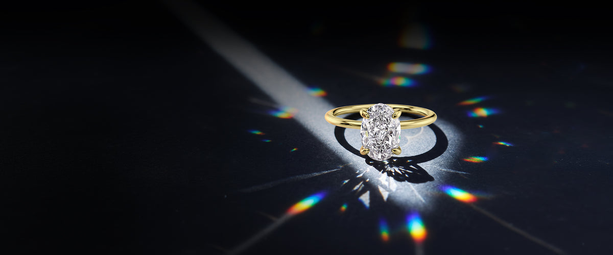 Pura Gems oval lab diamond solitaire ring in yellow gold on dark background with light refractions